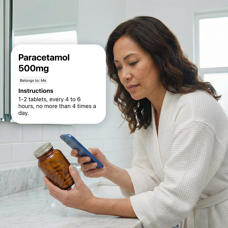 A woman in a white bathrobe scans a medicine bottle with her smartphone. The app overlay reads: Paracetamol 500mg. Belongs to: Me. Instructions: 1 to 2 tablets, every 4 to 6 hours, no more than 4 times a day.